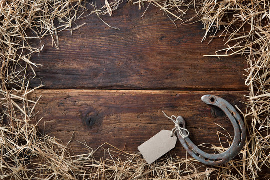 Horseshoe with an empty tag surrounded by straw on vintage wooden board