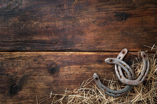 Two old rusty horseshoes with straw on vintage wooden board © Alexander Raths