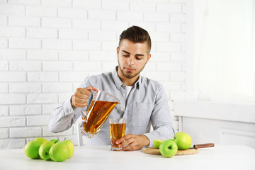 Fototapeta premium Young man man pouring apple juice into glass