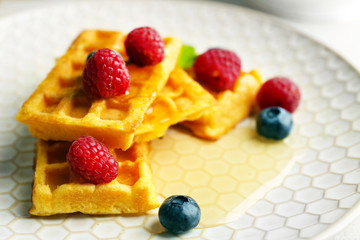Sweet homemade waffles with forest berries on plate, close-up