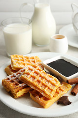 Sweet homemade waffles on plate, on light background