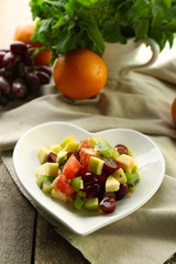 Fruit salad on plate, on wooden background