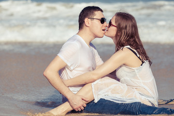 Loving couple sitting on the beach at the day time.