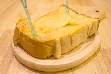 Bread toast and condensed milk on wooden plate