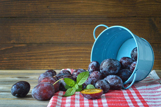 Plums and mint in the bowl on wooden background