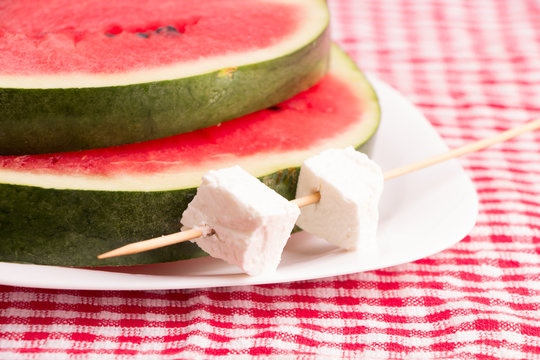 Watermelon slices & White cheese in plate, on a red tablecloth
