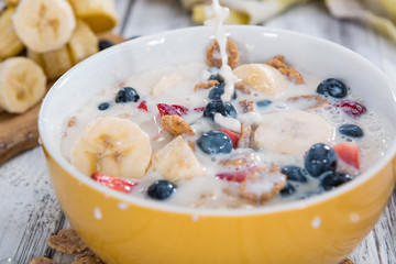 Pouring Milk on Cornflakes with fresh Fruits