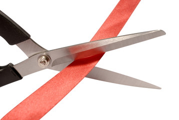 Scissors cutting red ribbon or tape close up isolated on white background photo