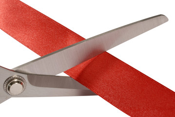 Scissors cutting red ribbon or tape close up closeup isolated on white background photo