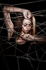 Beautiful young woman behind the interlaced ropes