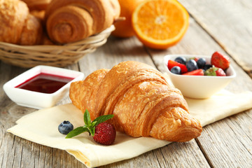 Fresh tasty croissants with berries on grey wooden background