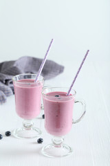 Fresh blueberry smoothie in the glasses on white wooden backgrou