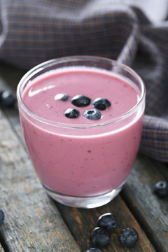 Fresh blueberry smoothie in the glasses on grey wooden backgroun