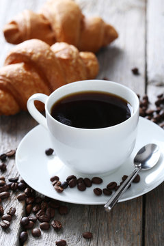 Delicious croissants with cup of coffee on grey wooden backgroun