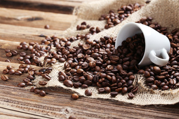 Coffee beans in cup on a brown wooden background