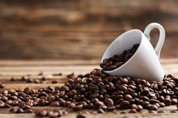 Coffee beans in cup on a brown wooden background