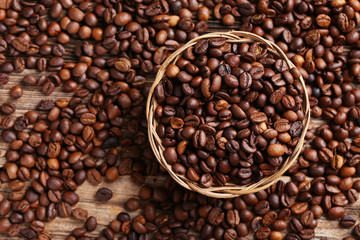 Roasted coffee beans in basket on a brown wooden background