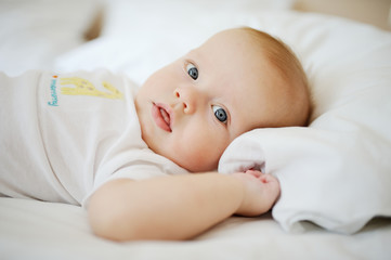 Portrait of a baby. Baby boy lying on the bed and looking at the