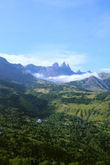 A green summer mountain landscape with the Aiguilles d'Arves peak in the far