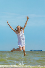 Happy girl jumping over the sea