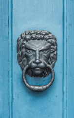 Iron lion knocker on the old blue wooden door 