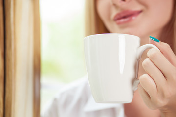 Cheerful young girl is drinking hot coffee
