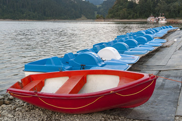 Czerwona łódka i niebieskie rowery wodne - obrazy, fototapety, plakaty