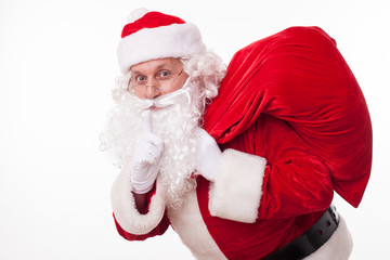 Cheerful Santa Claus is carrying presents secretly