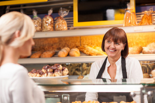 Cheerful saleswoman is serving a customer in bakery