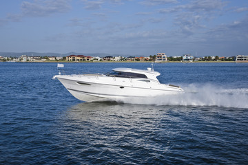 White yacht sailing across a coast