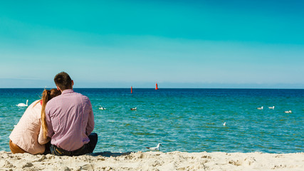 Fototapeta na wymiar couple sitting on beach rear view