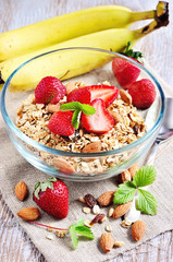Granola cereal with fresh strawberries, raisins, almonds, and yogurt, selective focus