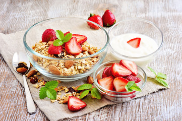 Granola cereal with fresh strawberries, raisins, almonds, and yogurt, selective focus