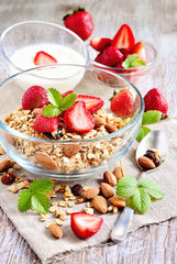 Granola cereal with fresh strawberries, raisins, almonds, and yogurt, selective focus