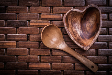 Set of heartshaped wood bowl and spoon on wooden backcloth