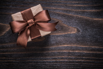 Giftbox with brown tied bow on vintage wooden board