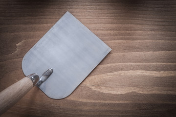 Metal bricklaying trowel on vintage wood board construction conc