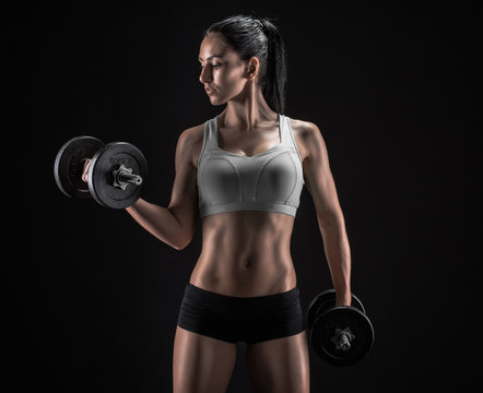 Young woman lifting the dumbbells