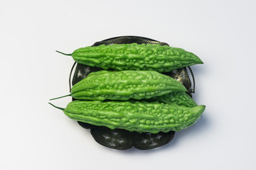 Whole karela bitter melon caraili studio close up white background inside metal basket