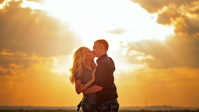 Loving couple kissing at sunset.
