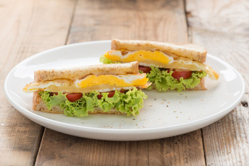 Sandwichs fried egg with cheese on white plate .