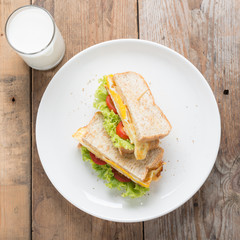 Sandwichs fried egg with cheese and milk on wood table.