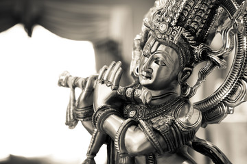 Black and white statue of the Hindu God Krishna playing a flute