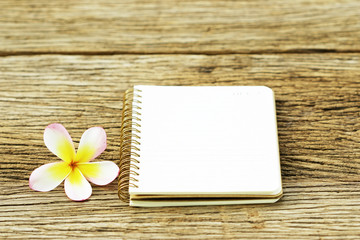 Fototapeta na wymiar Notebook and plumaria flower on wood table