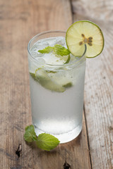 Cold fresh lemonade soda drink on a wooden background.