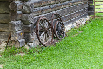 Fototapeta na wymiar Old wooden wheels of cart on barn wall, rural concept