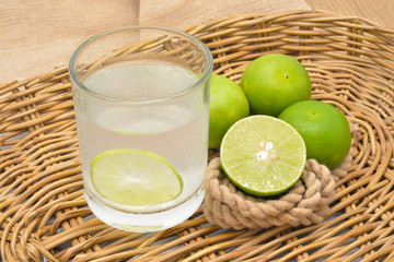 Lemonade with fresh green lemon on rattan basket
