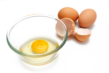 raw eggs yolk in a glass bowl on a white background.