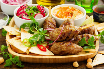 Kyufta (barbecue) of lamb with snacks (radish salad, chips and hummus.)