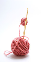 Marsala-colored woolen yarn and knitting needle.